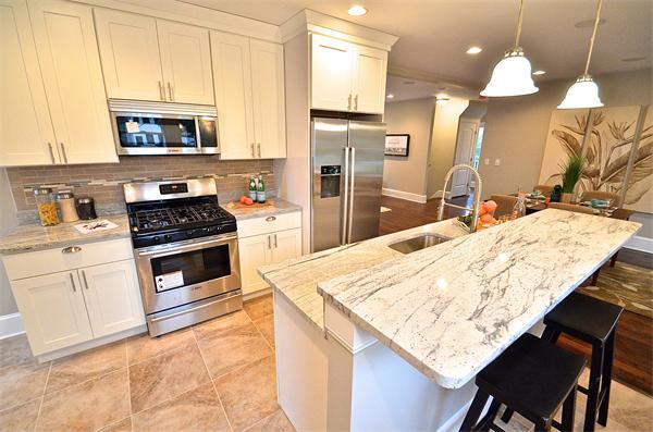 a kitchen with stainless steel appliances kitchen island a table chairs and a refrigerator
