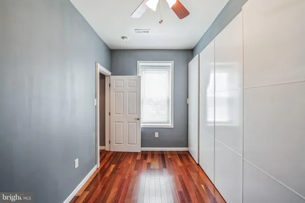 a view of empty room with wooden floor and fan