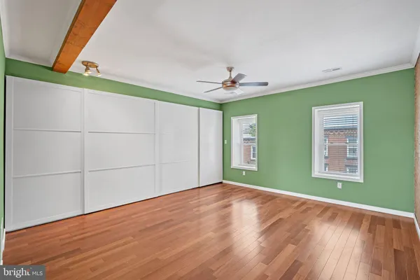 a view of an empty room with a window and wooden floor