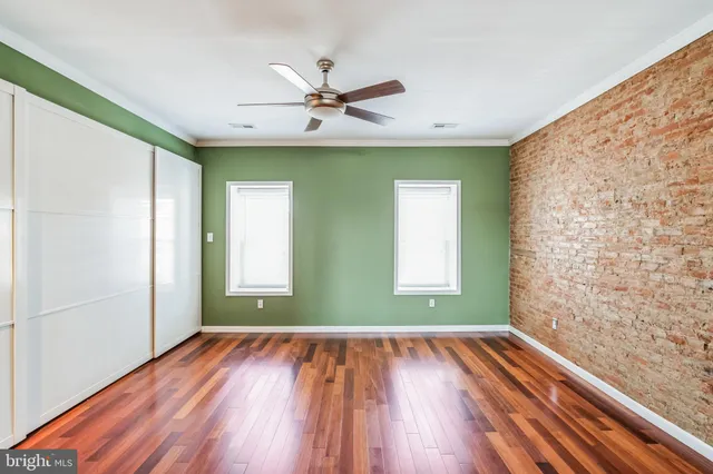 a view of empty room with wooden floor and fan