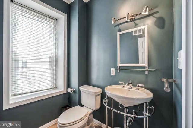 a bathroom with a toilet a sink a mirror and a window