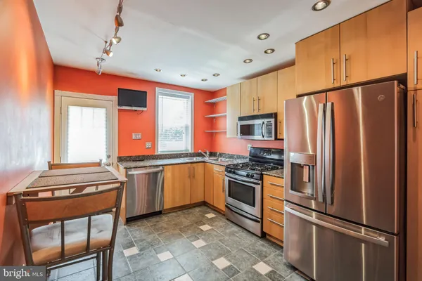 a kitchen with stainless steel appliances granite countertop a refrigerator a stove and a sink