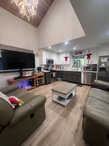 a living room with stainless steel appliances furniture and a flat screen tv