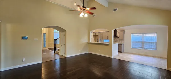 a view of an empty room with a window and wooden floor