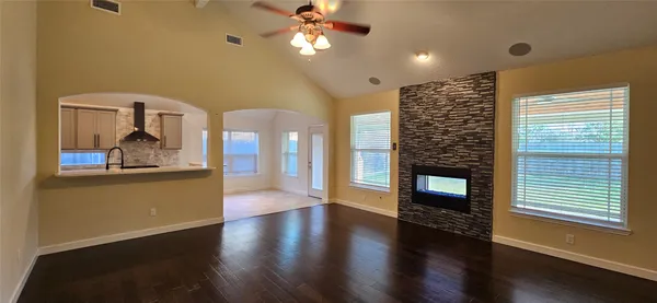 a view of a livingroom with furniture wooden floor a ceiling fan and windows