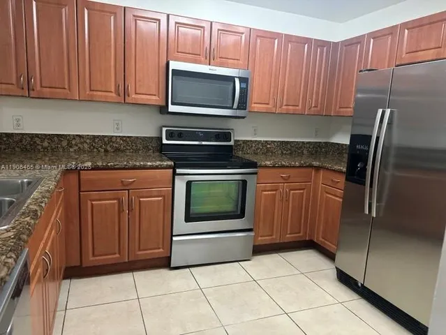 a kitchen with granite countertop a refrigerator and a stove top oven