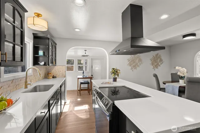 a kitchen with stainless steel appliances kitchen island granite countertop a sink a stove and a wooden floors