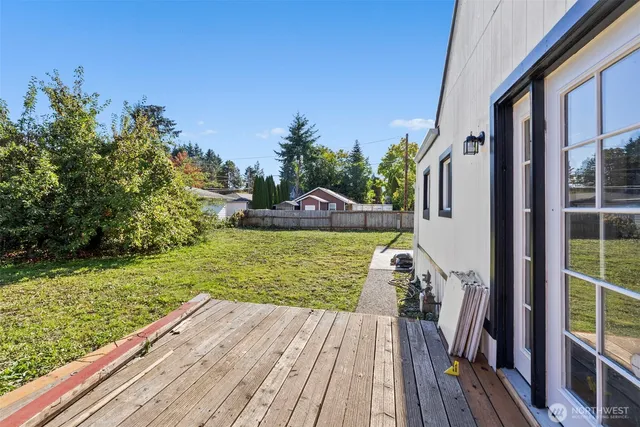 a view of a deck with a big yard potted plants and large tree