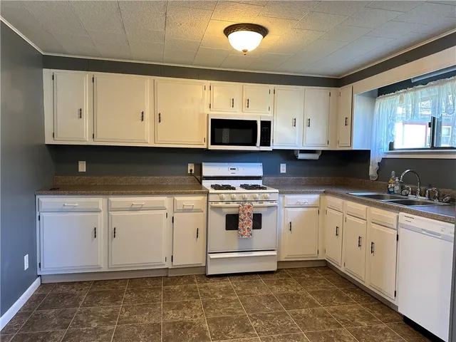 a white kitchen with granite top and stainless steel appliances