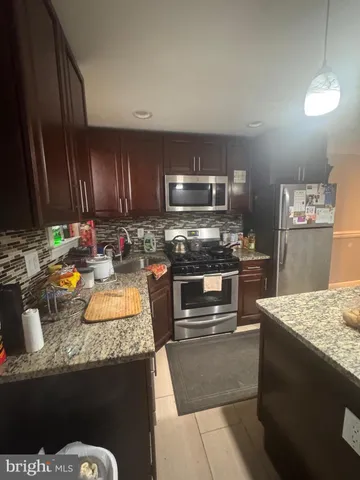 a kitchen with granite countertop a sink stove and refrigerator