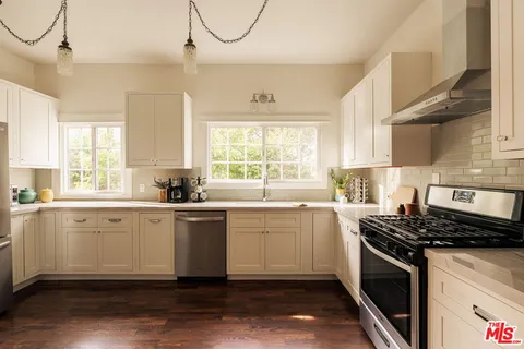 a kitchen with stainless steel appliances a stove a sink and white cabinets
