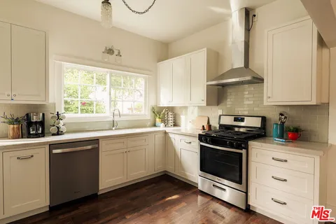 a kitchen with a refrigerator a sink cabinets wooden floor and a window