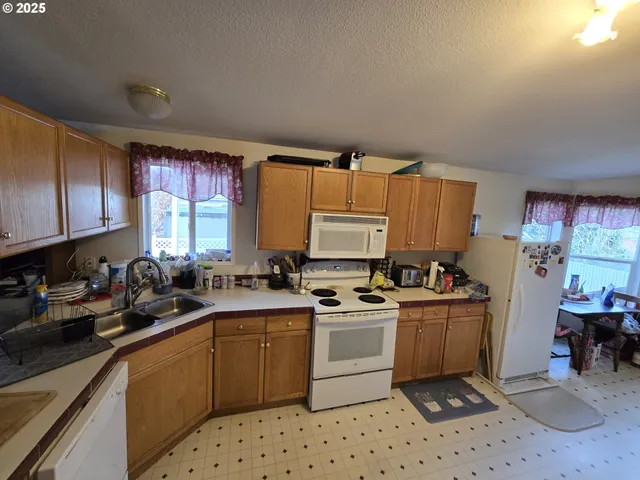 a kitchen with a sink a stove a refrigerator cabinets and a window