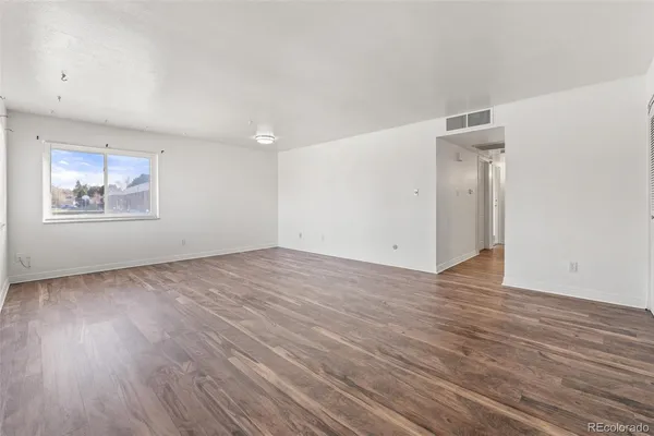 an empty room with wooden floor and windows