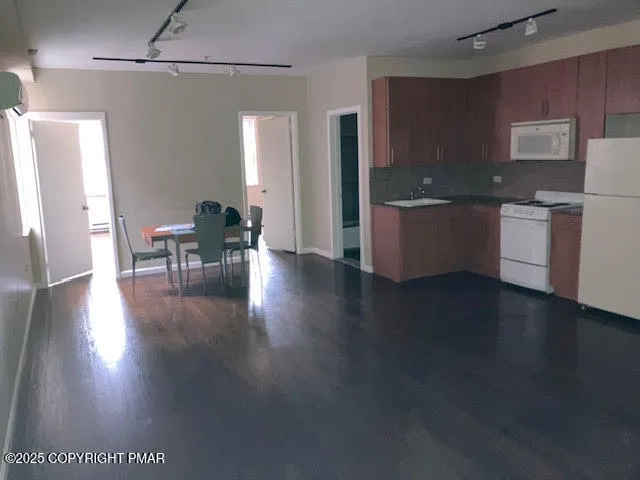 a kitchen with stainless steel appliances granite countertop a refrigerator a sink a stove and a wooden floors