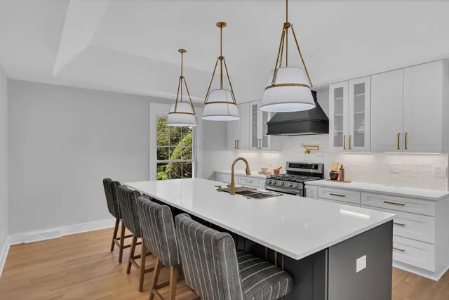 a kitchen that has a kitchen island a stove a counter space and a sink