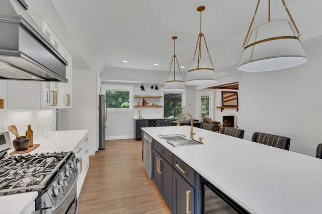 a kitchen with stainless steel appliances a sink a stove and chairs