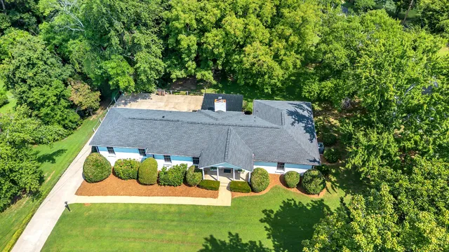 an aerial view of residential house with outdoor space and trees all around