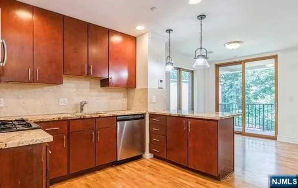 a kitchen with stainless steel appliances granite countertop wooden cabinets a refrigerator and a sink