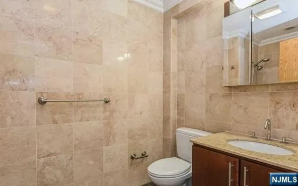 a bathroom with a granite countertop sink a toilet and shower