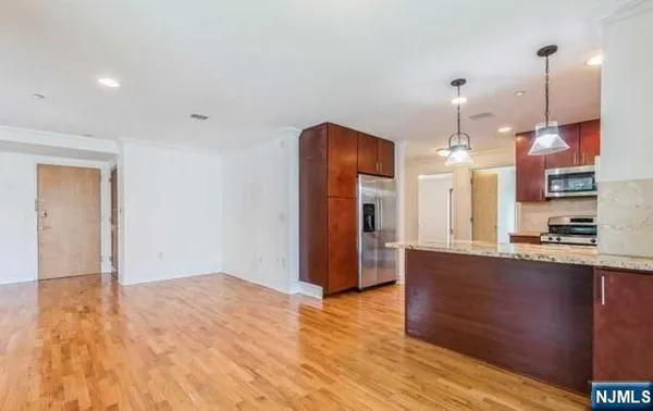 a view of a kitchen with stainless steel appliances granite countertop a refrigerator a sink and wooden floor