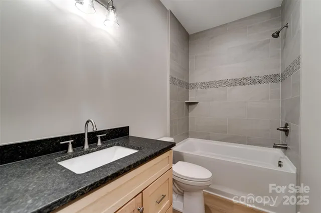 a bathroom with a granite countertop sink and a toilet