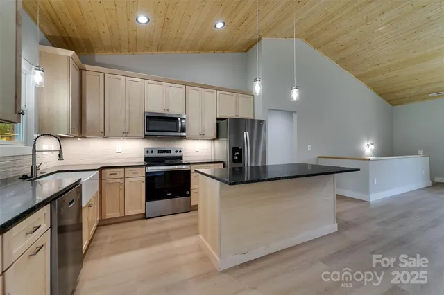 a kitchen with stainless steel appliances a stove a sink a microwave a refrigerator and cabinets