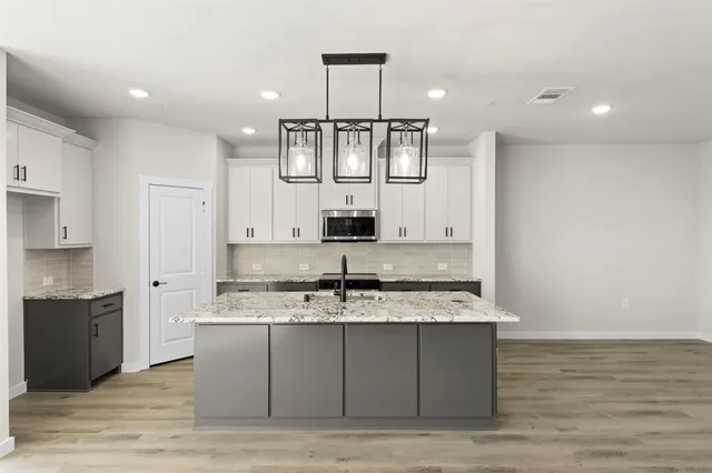 a large kitchen with stainless steel appliances granite countertop a sink and cabinets
