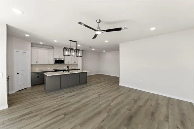 a large kitchen with a center island wooden floor and stainless steel appliances