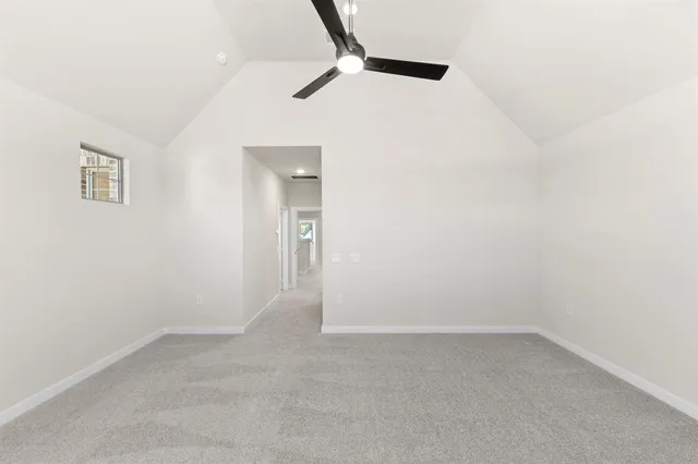 an empty room with a ceiling fan and carpet