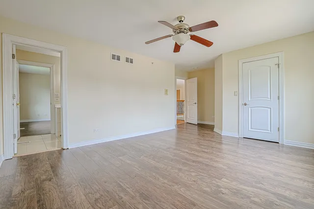 an empty room with wooden floor and ceiling fan