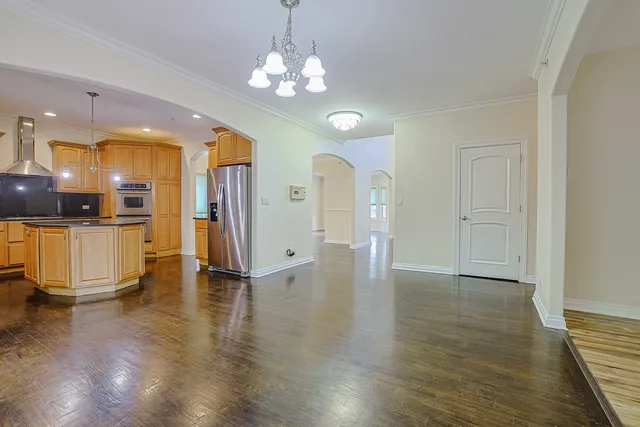 a view of a hallway with wooden floor and a kitchen