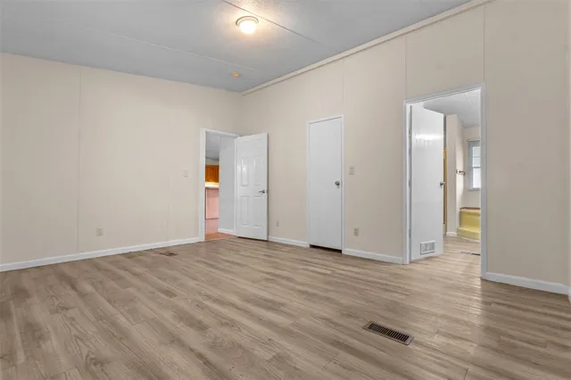 a view of an empty room with wooden floor and closet
