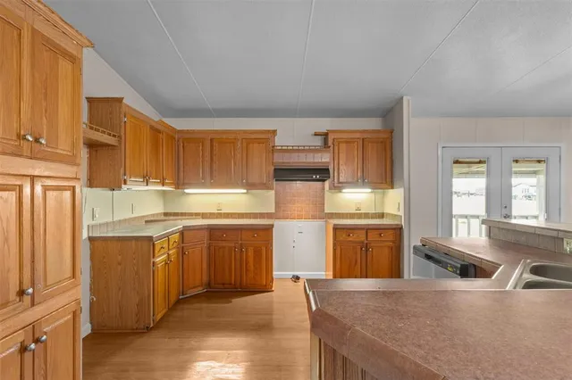 a kitchen with stainless steel appliances granite countertop a stove a sink dishwasher and a refrigerator with wooden cabinets