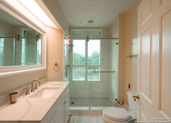 a bathroom with a granite countertop sink toilet mirror vanity and shower