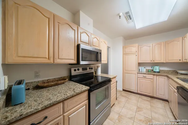 a kitchen with granite countertop white cabinets sink and stainless steel appliances