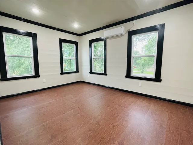 a view of an empty room with wooden floor and windows
