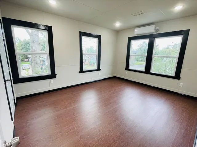 an empty room with wooden floor and windows
