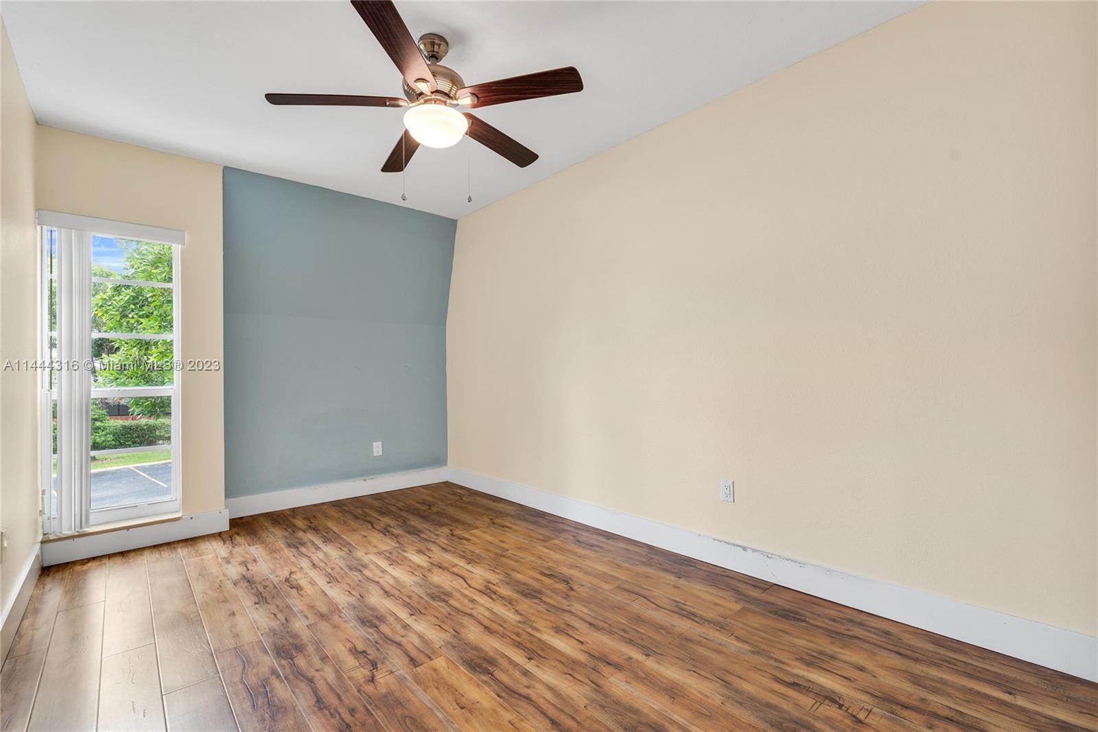 14001 Southwest 84th Street, Unit 1308 Miami, FL 33183 - Photo 23 of 47 an empty room with wooden floor chandelier fan and windows