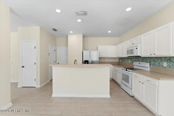 a large white kitchen with cabinets