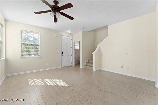 a view of empty room with wooden floor and fan