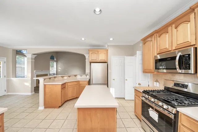 a large kitchen with kitchen island a sink a stove and a window