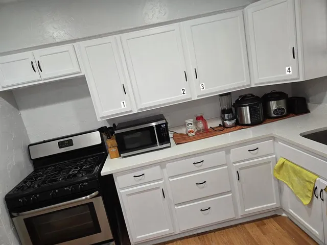 a kitchen with white cabinets and black appliances