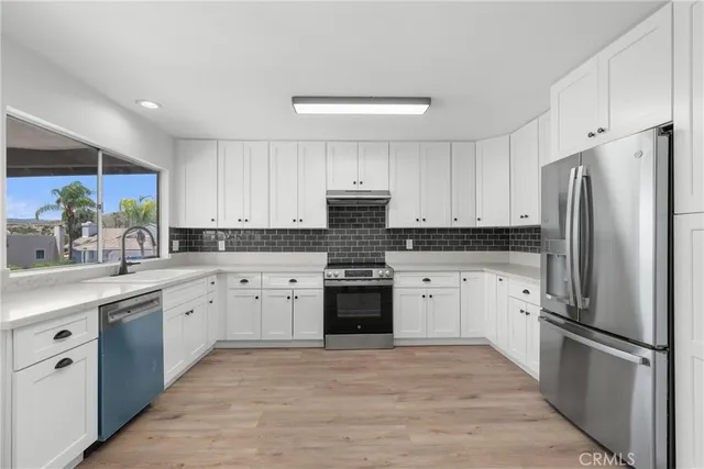 a kitchen with white cabinets and stainless steel appliances