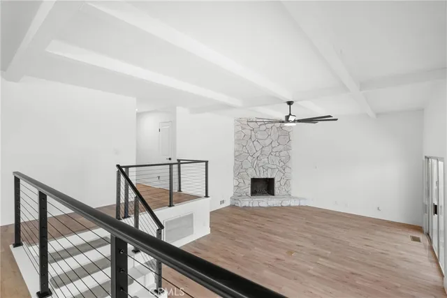 a view of empty room with wooden floor and fan