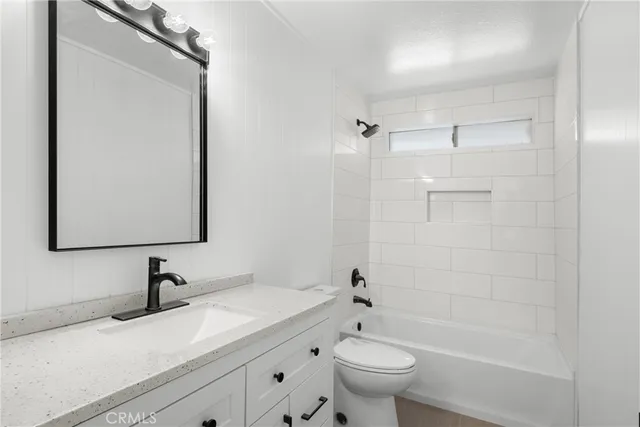 a bathroom with a granite countertop sink a toilet and shower