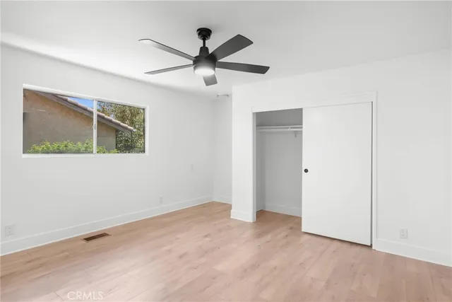 a view of a big room with wooden floor closet and ceiling fan
