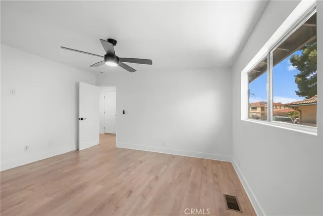 a view of an empty room with a window and wooden floor