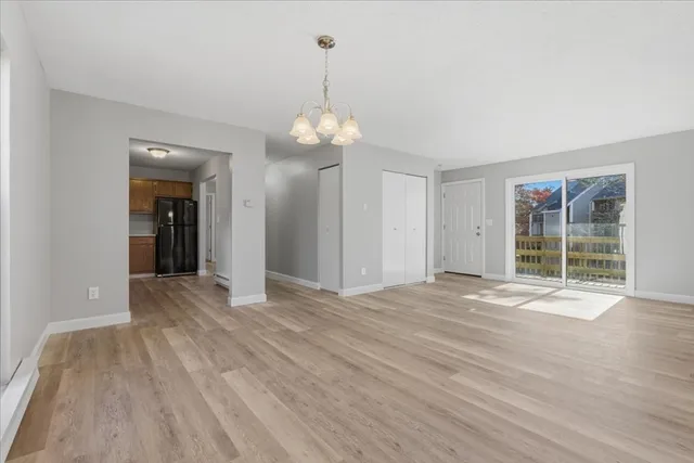 an empty room with wooden floor cabinet and windows