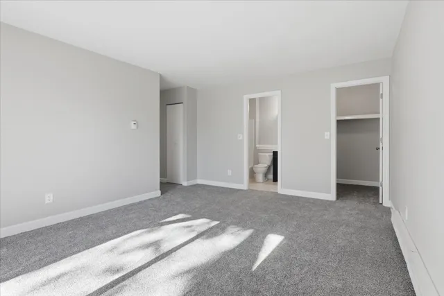 a view of an empty room with closet and a window